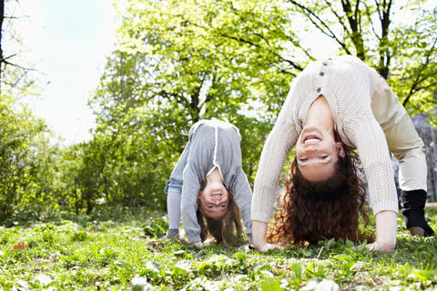Mutter und Tochter machen Sport draußen auf der Wiese